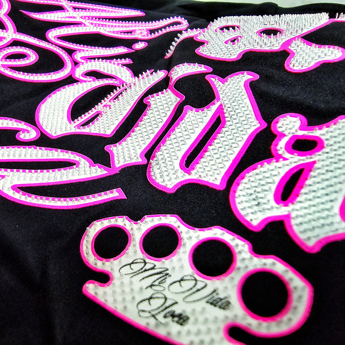 Primo piano della stampa Babe Skull rosa e bianca con logo MVL sul top nero
