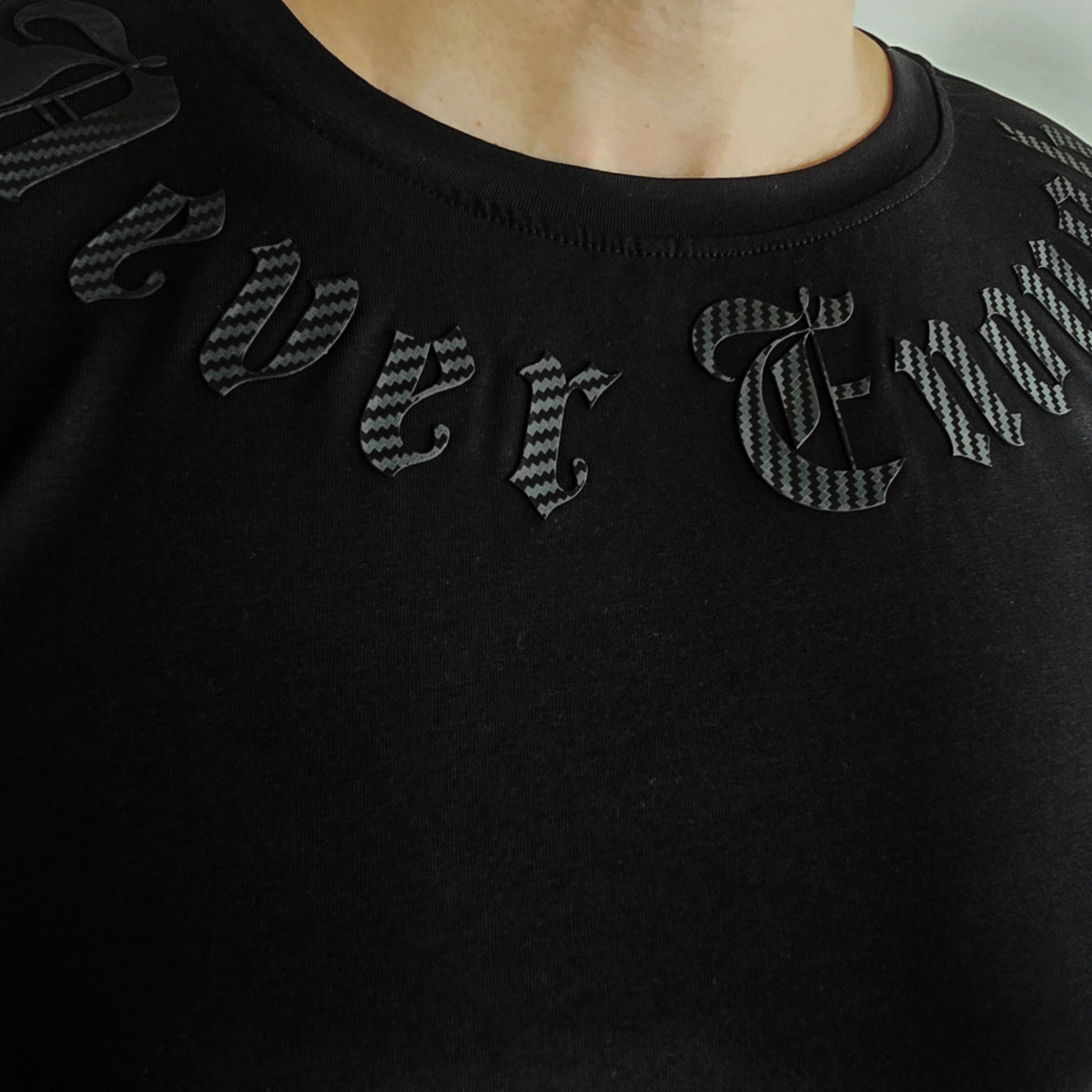 Primo piano delle lettere nere Never enough intorno allo scollo della T-shirt Gold line