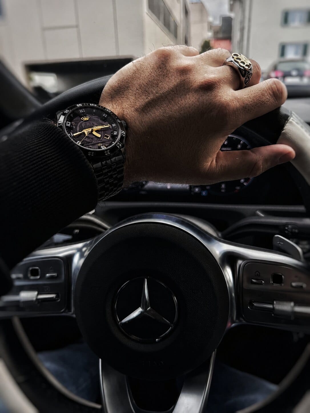 Montre automatique MVL AK47 noire au poignet d'une main sur le volant d'une voiture