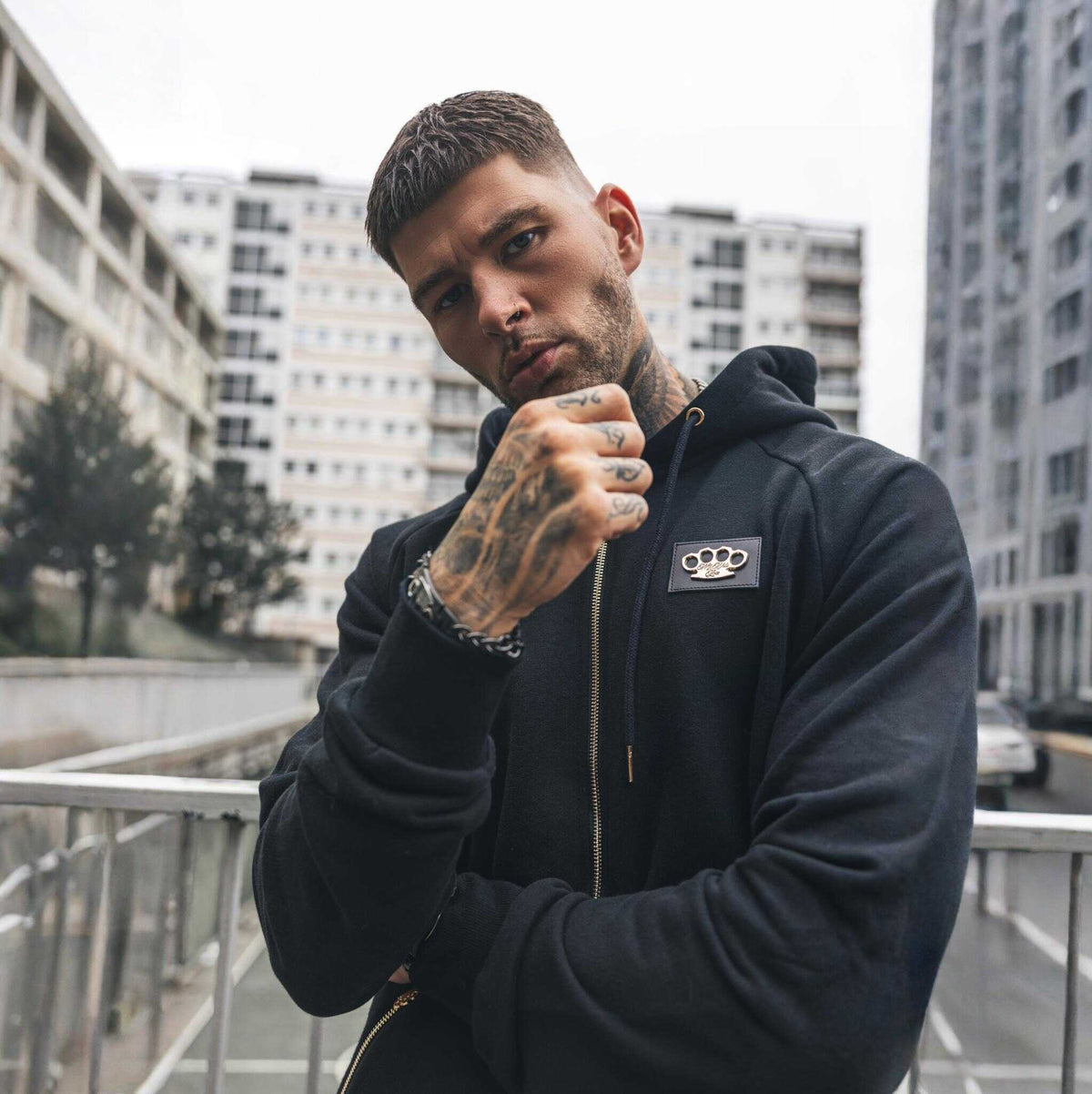 Model in de zwarte MVL Cupid with gun hoodie met rits en MVL logo patch op de borst, voorkant