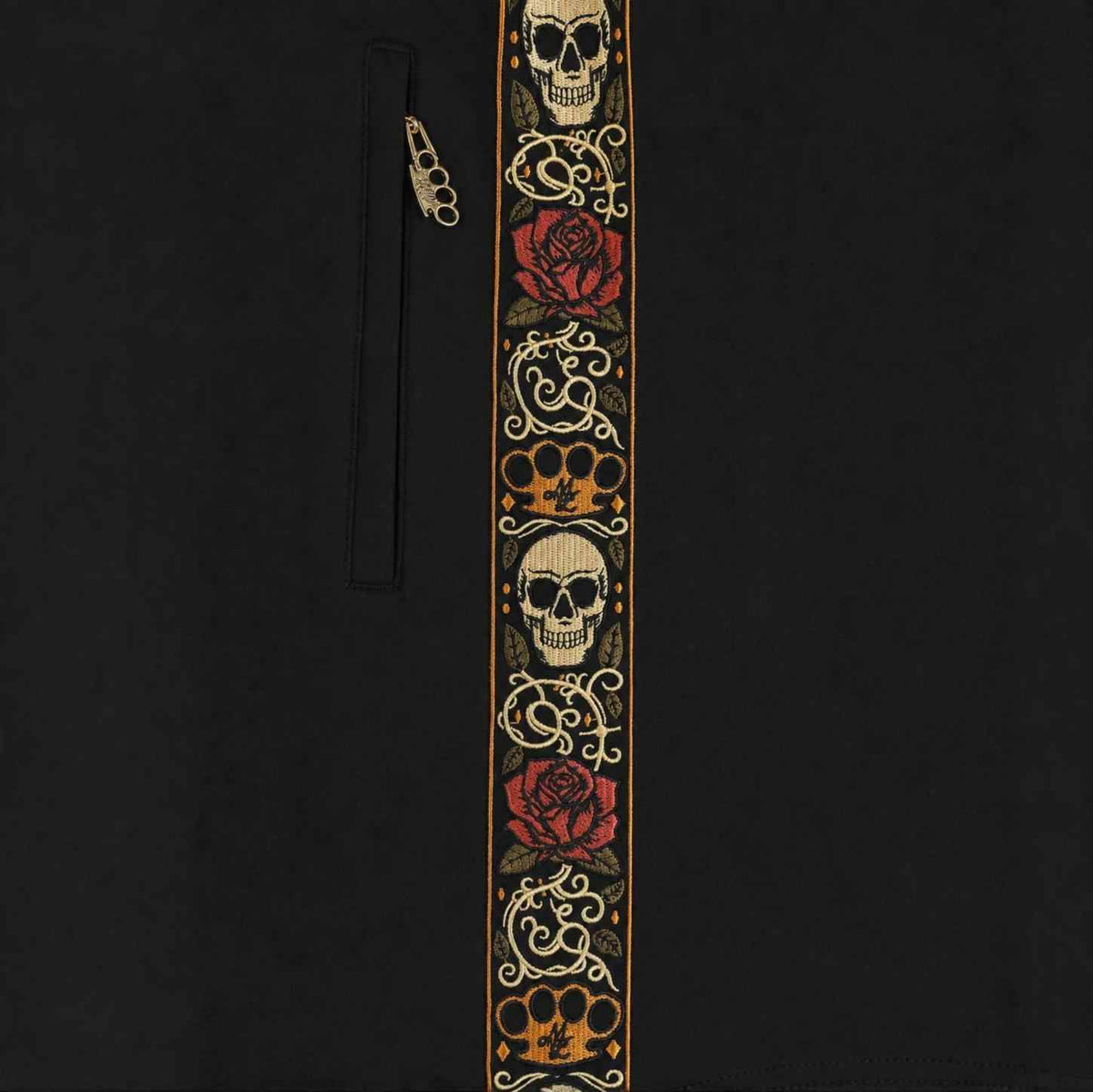 Primer plano de la banda bordada Calavera con calaveras, rosas y logo MVL junto a la cremallera del bolsillo