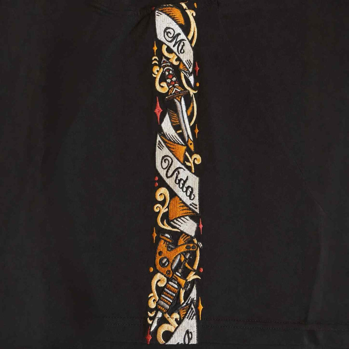 Close-up van de Savage ornate schouderband met dolk, rozen en Mi Vida Loca banner