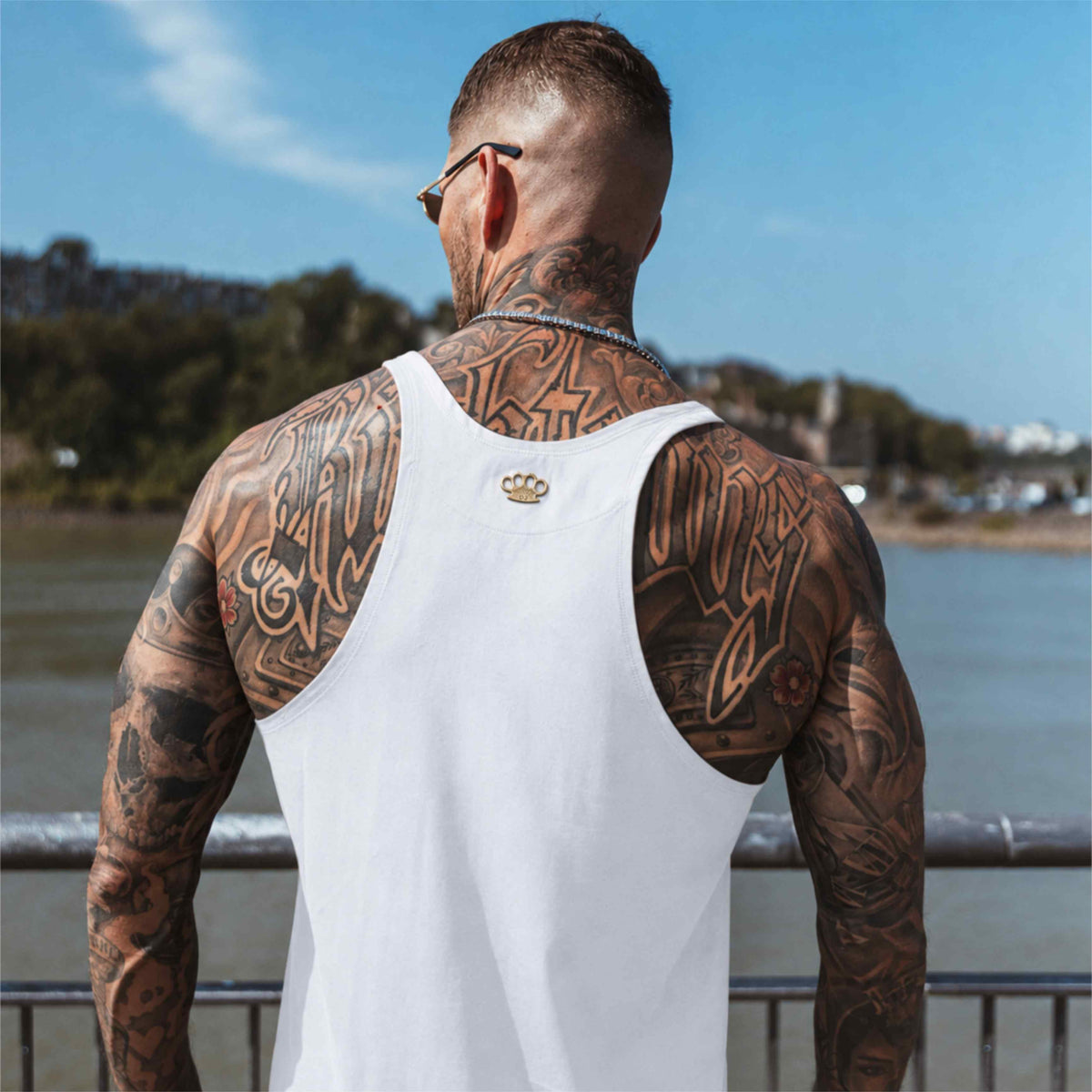 Achterkant van de witte MVL Original streetwear tanktop gedragen door model met rugtattoos