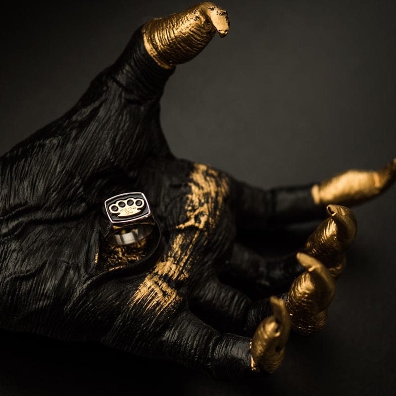 Anello con sigillo MVL argento su una scultura di mano nera e oro, foto d'atmosfera