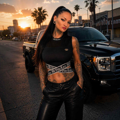 Mi Vida Loca Signature Women top in black worn by model with leather pants by a black pick-up truck